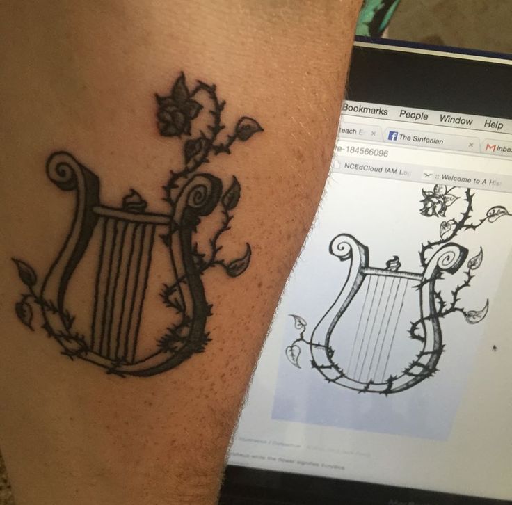 a tattoo on the leg of a man with a harp and flowers in it, next to a computer screen