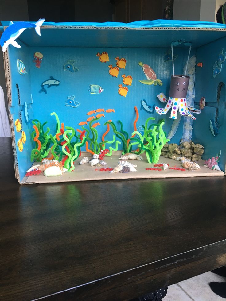 an ocean scene made out of cardboard on top of a wooden table with fish and corals