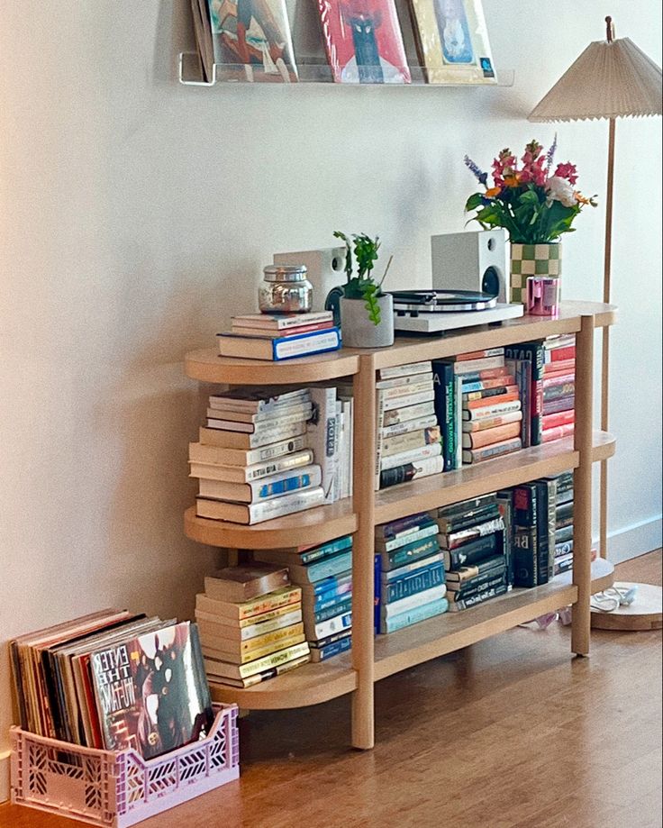 a bookshelf filled with lots of books on top of a hard wood floor