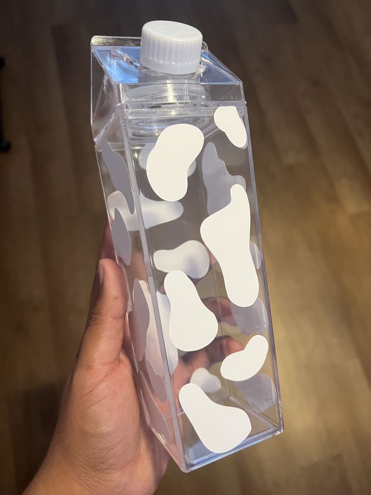 a hand holding a plastic bottle with white dots on it