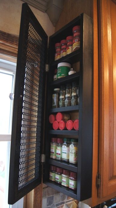 an open cabinet in the corner of a kitchen filled with spices and condiments