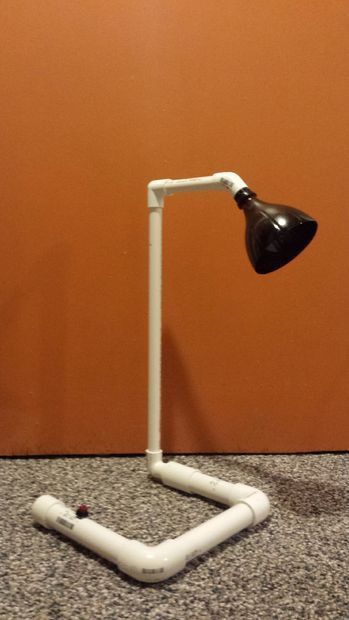 a black and white desk lamp sitting on top of a floor next to a wall