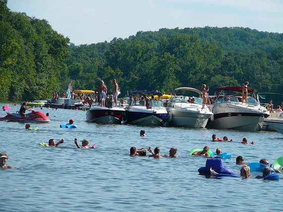 many people are swimming in the water near boats