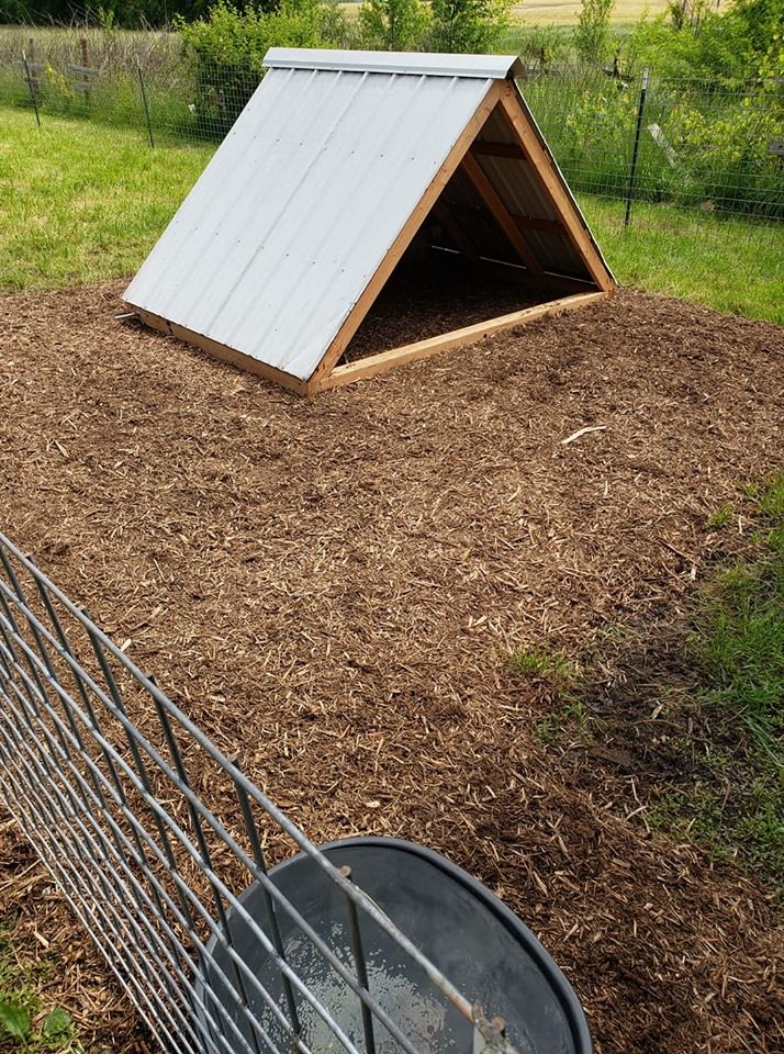 an animal pen with a dog house in the middle of it's back yard