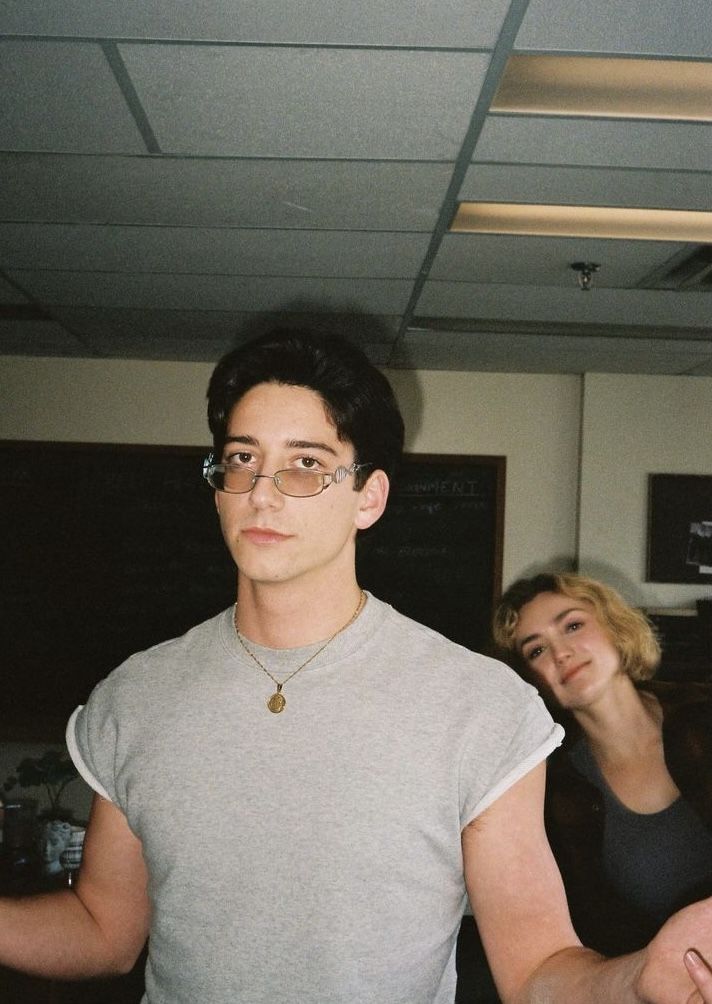 a young man wearing glasses standing next to a woman