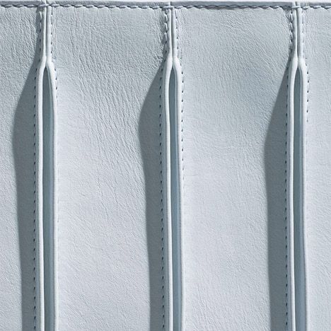 three toothbrushes sticking out of the side of a white leather case with stitching