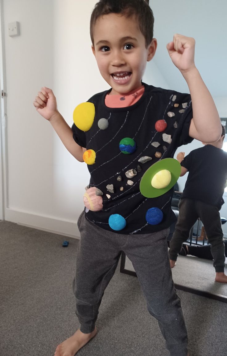 a young boy standing in front of a mirror with his arms up and hands raised