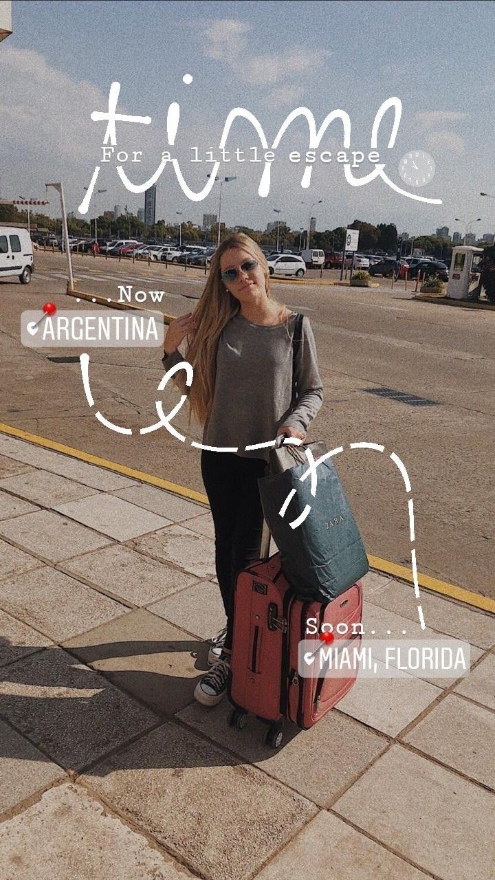 a woman standing on the sidewalk with her luggage