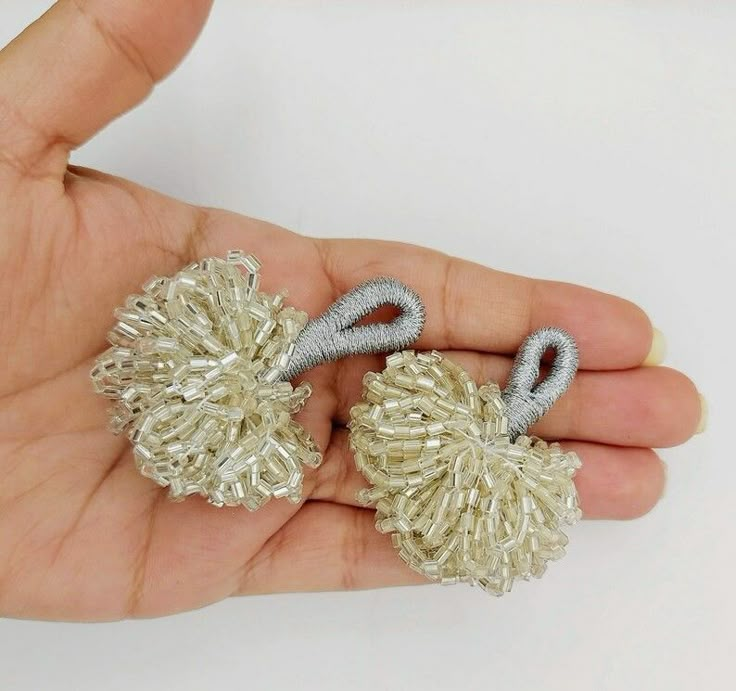 someone is holding two small silver and white pom - poms in their hand