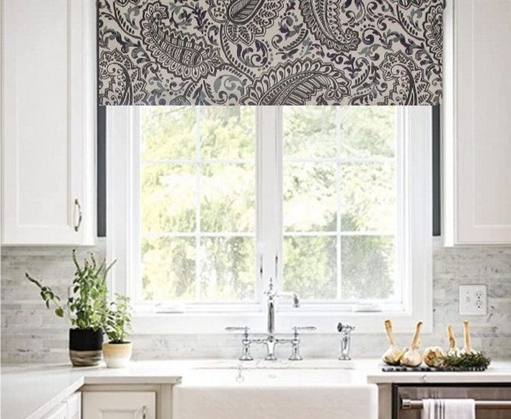 a kitchen with a sink and window covered in blue paisley print roman shades over the windows