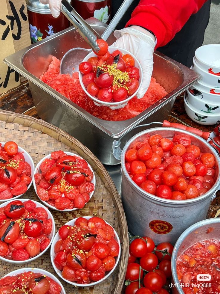 several buckets filled with red tomatoes on top of a table next to other bowls