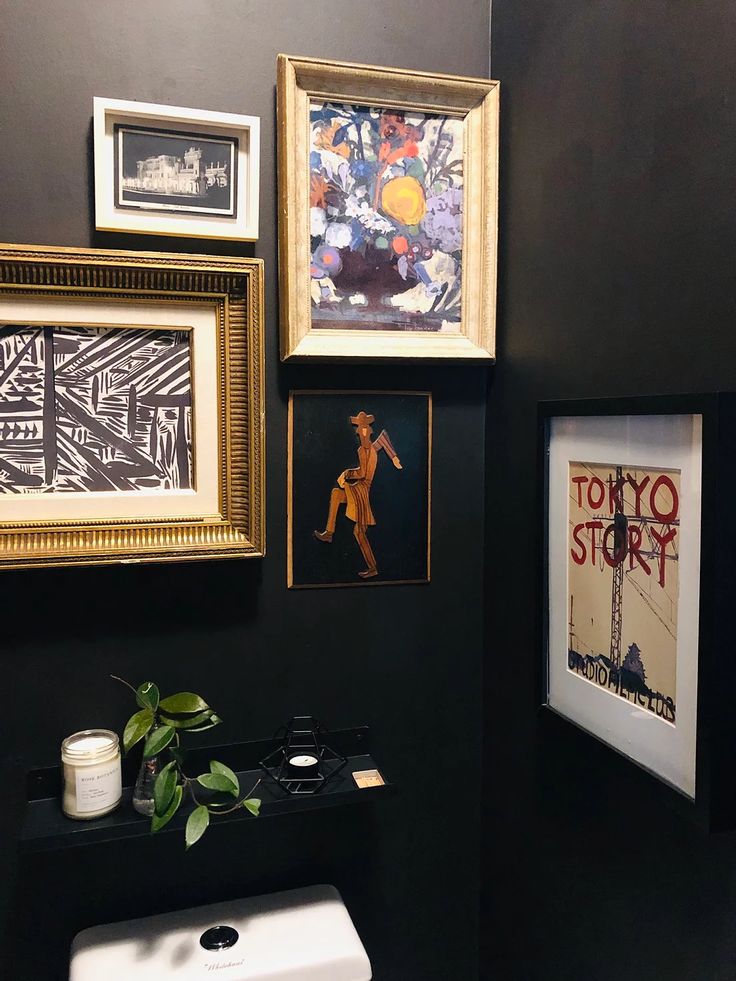 a bathroom with black walls and pictures on the wall