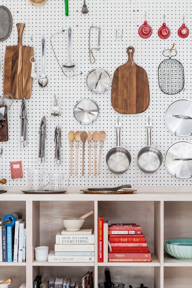 kitchen utensils and cookbooks are hanging on the pegboard in this organized pantry