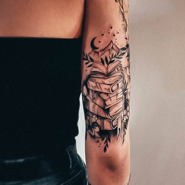 a woman with a tattoo on her arm is holding a stack of books and looking at the camera