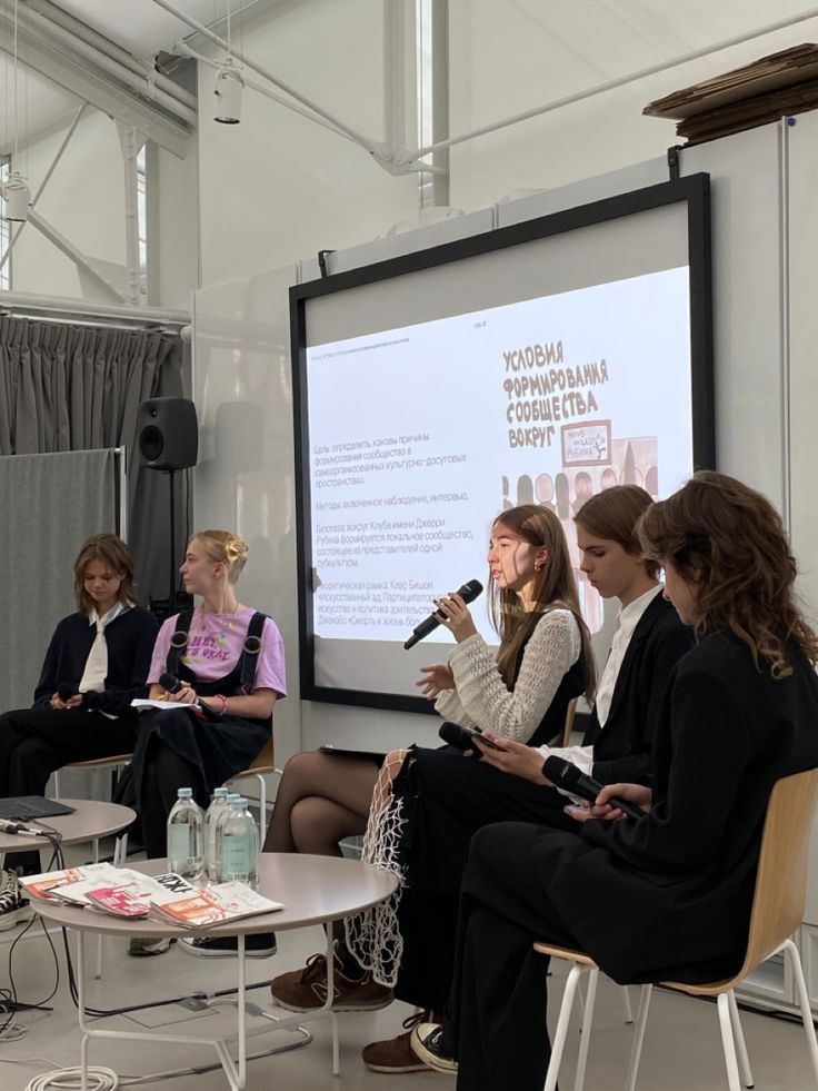 several women sitting in chairs and talking to each other while one woman holds a microphone