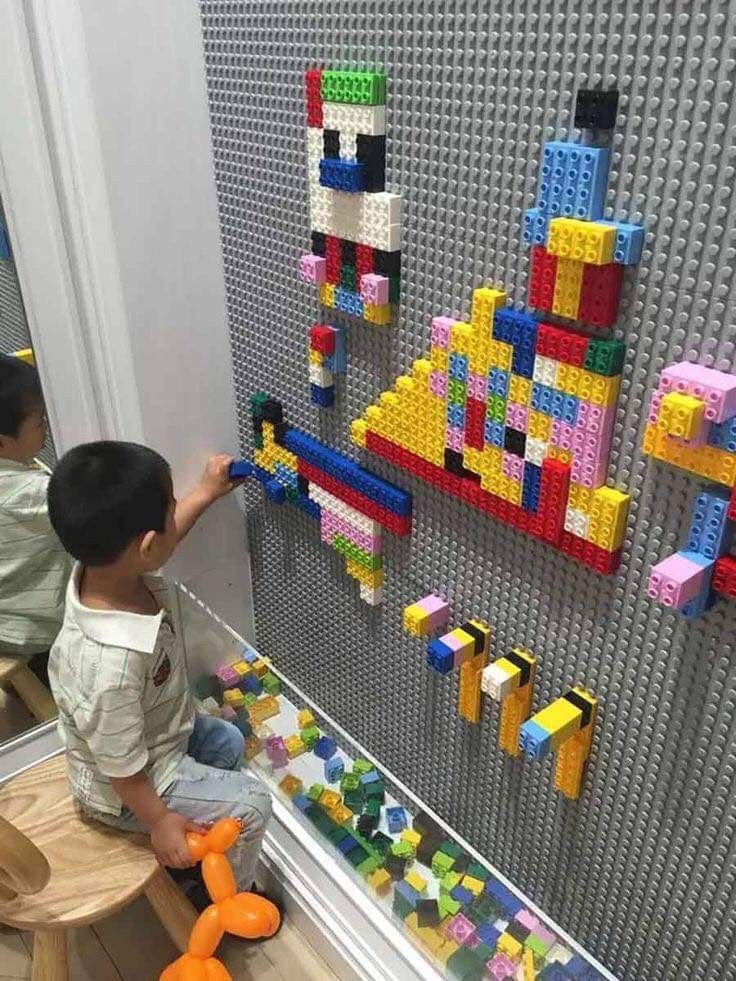 two children playing with legos on the wall