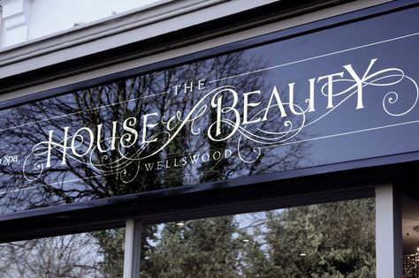 the front window of a beauty shop with trees in the background