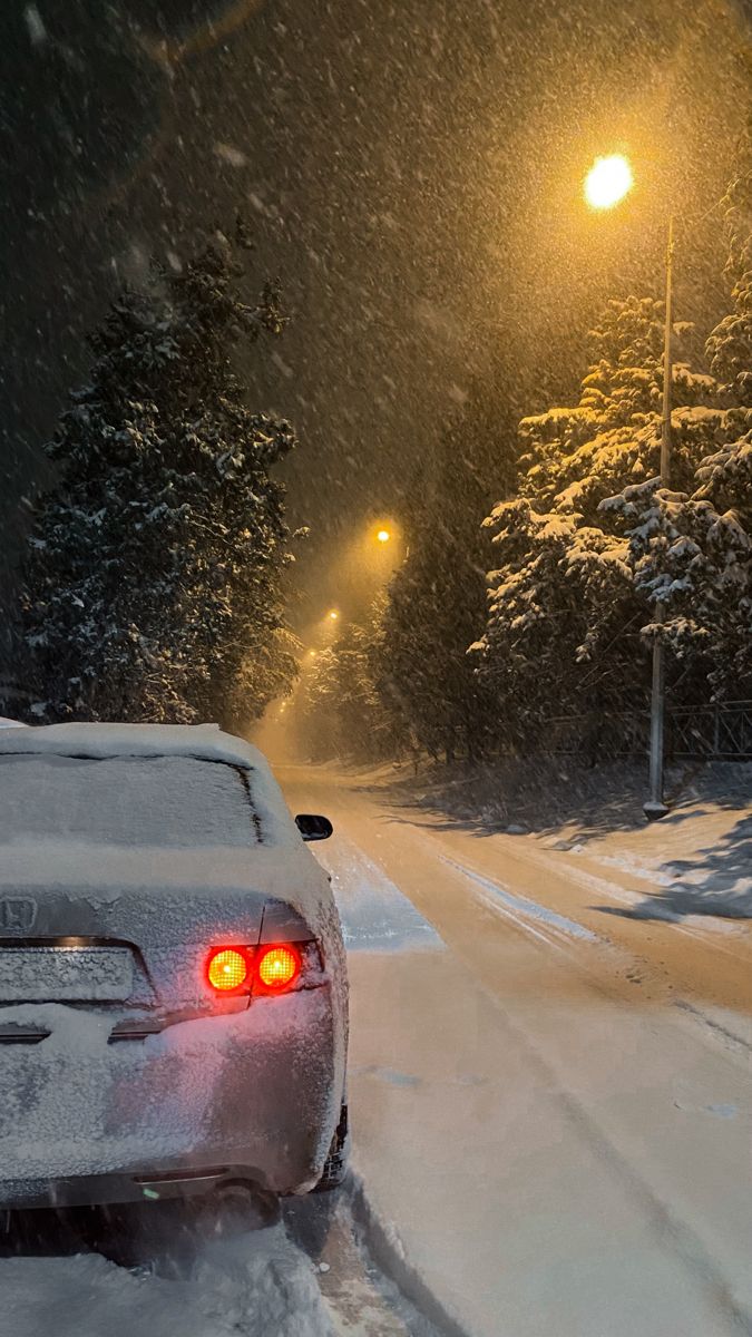 a car driving down a snow covered road at night