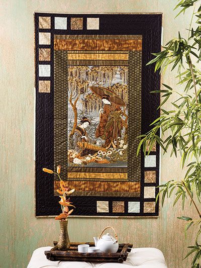 a wall hanging on the side of a green wall next to a table with a vase