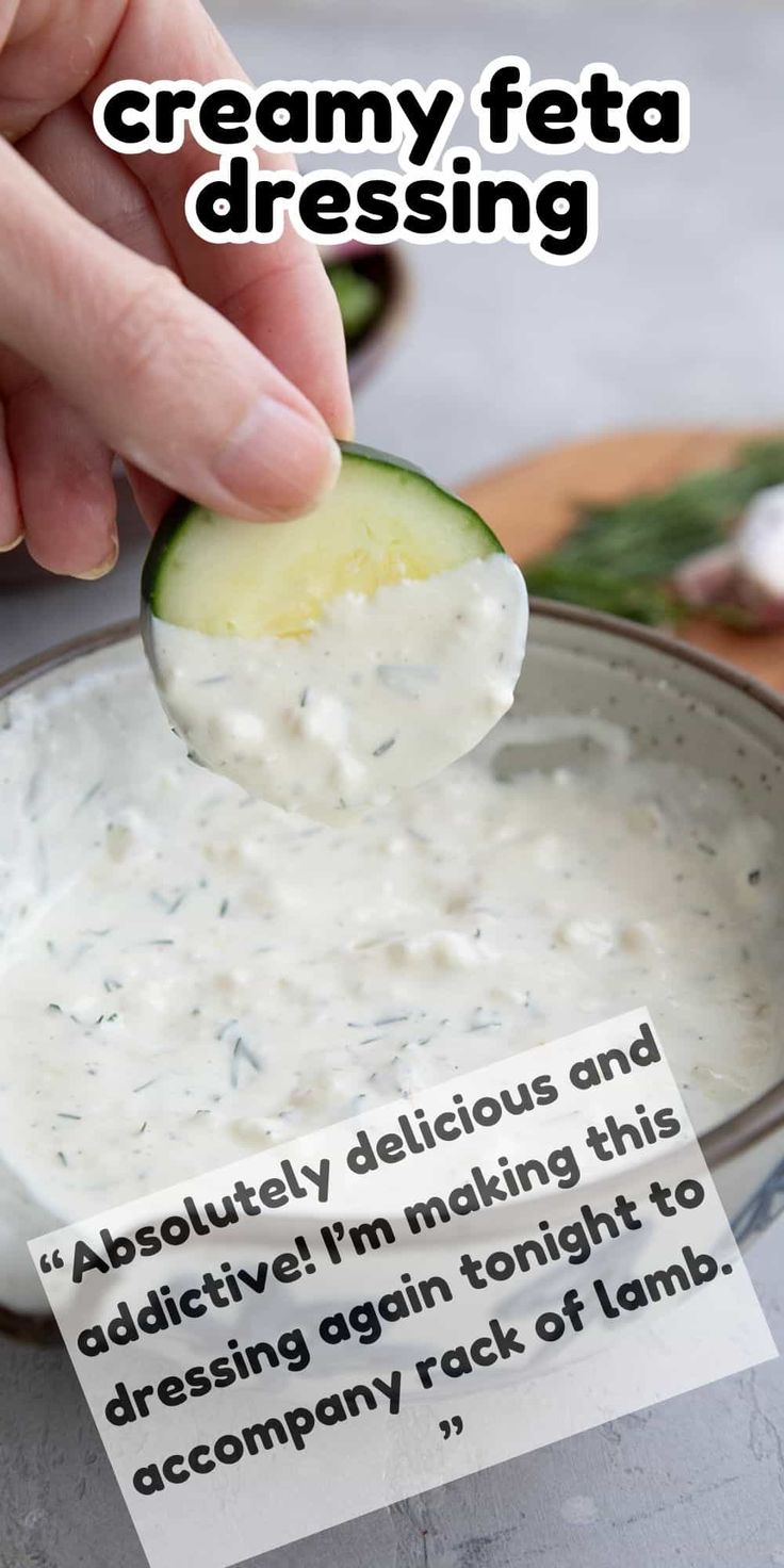 a person dipping a cucumber into a bowl of creamy feta dressing