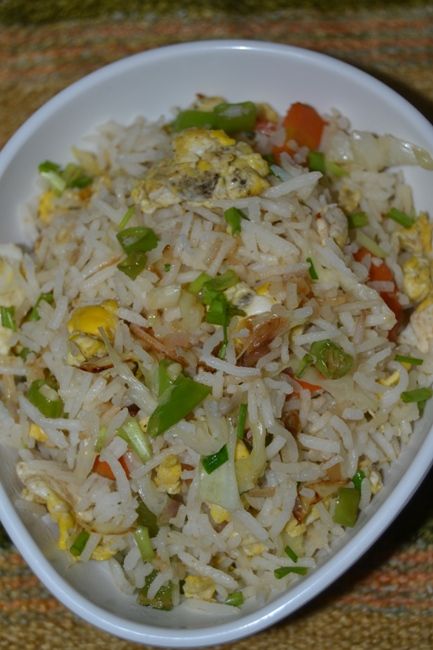 a white bowl filled with rice and veggies on top of a brown table