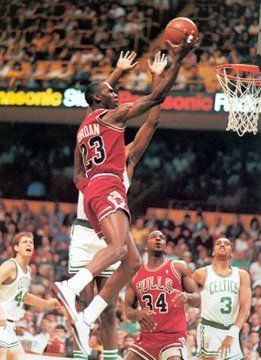 a basketball player jumping up to dunk the ball in front of two other players