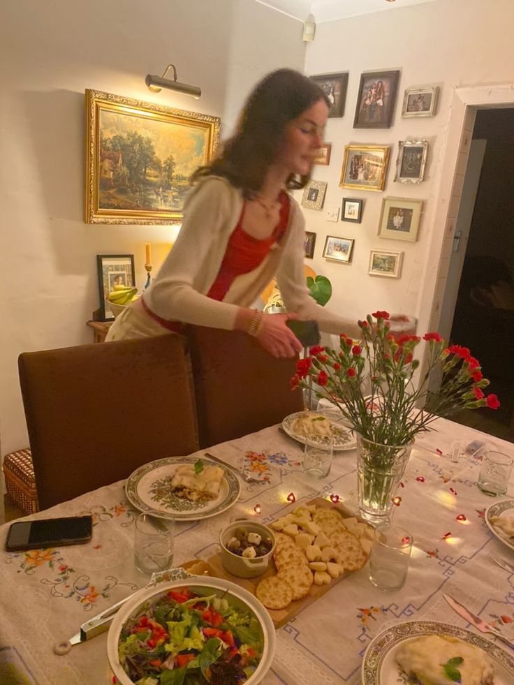 a woman sitting at a table with plates of food and flowers in front of her