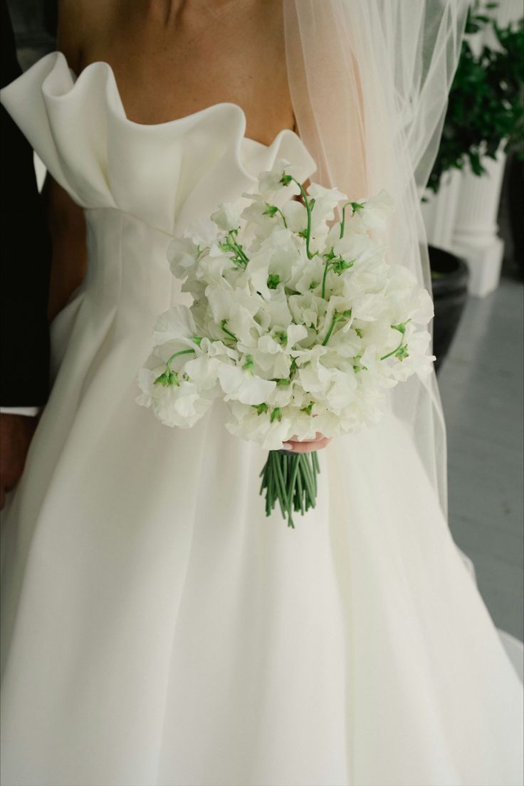 the bride is holding her bouquet of white flowers