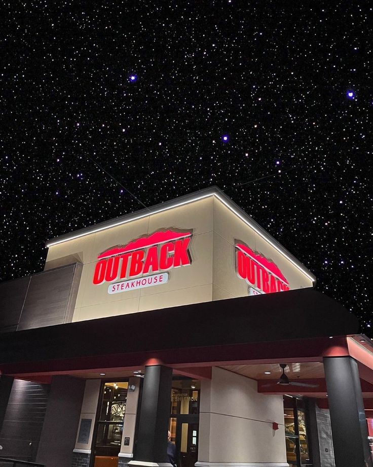 the outside of a store at night with stars in the sky above and below it