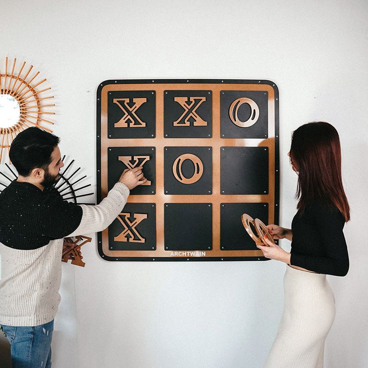 two people standing next to each other in front of a giant tic - board