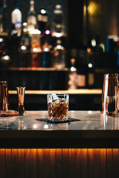 an image of a bar with drinks on the counter and lights in the back ground