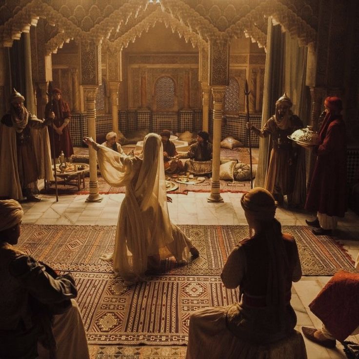 a group of people dressed in medieval clothing sitting on rugs and talking to each other