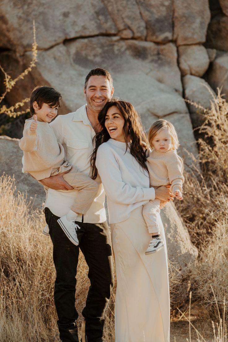 a man, woman and child standing in front of a rock formation with their arms around each other