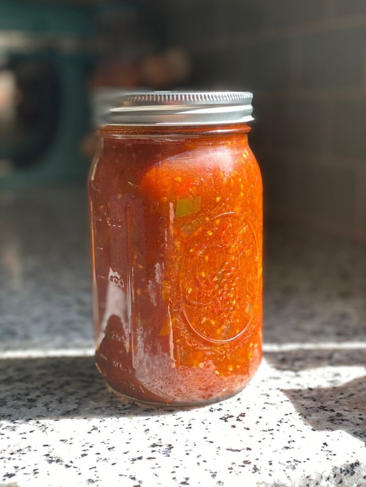 a glass jar filled with red liquid sitting on top of a counter