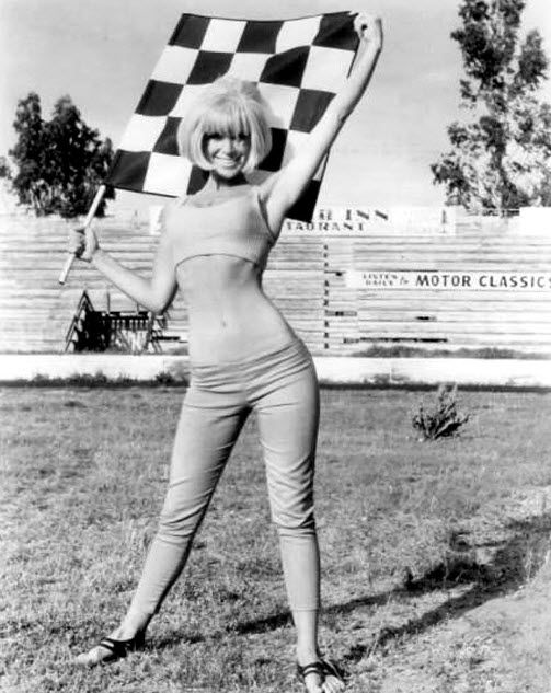 an old photo of a woman holding a checkered flag