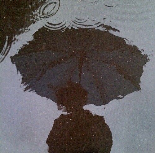 an umbrella is reflected in the water on a wet surface with ripples and drops