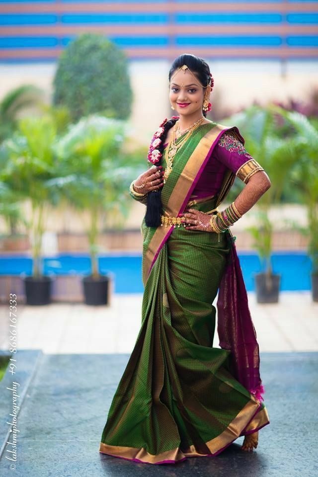 a woman in a green and purple sari standing with her hands on her hips