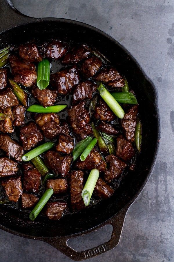 beef and asparagus stir fry in a cast iron skillet with tongs