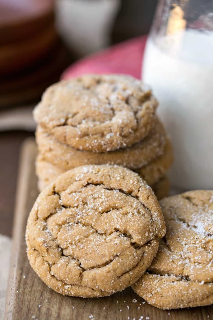 several cookies on a wooden board next to a glass of milk