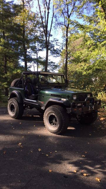 a green jeep is parked on the side of the road in front of some trees