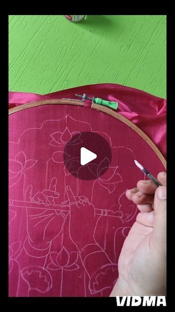 someone is working on an embroidery project with scissors and thread in front of a green wall