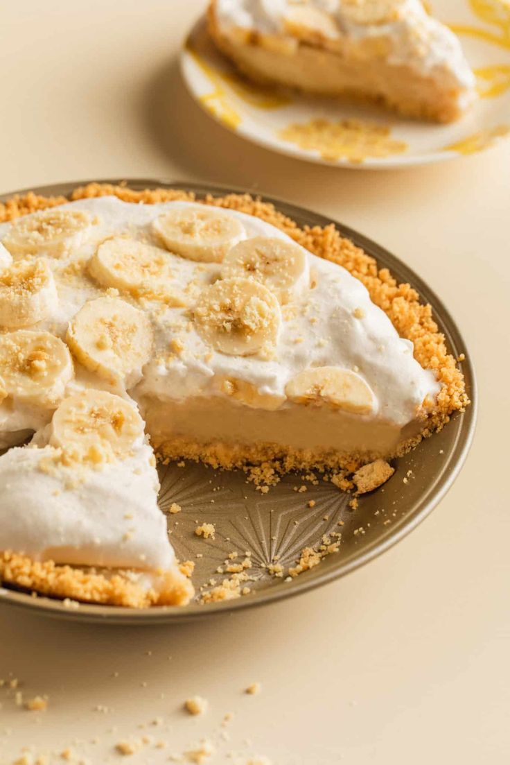 a banana cream pie on a plate with one slice cut out and another half eaten