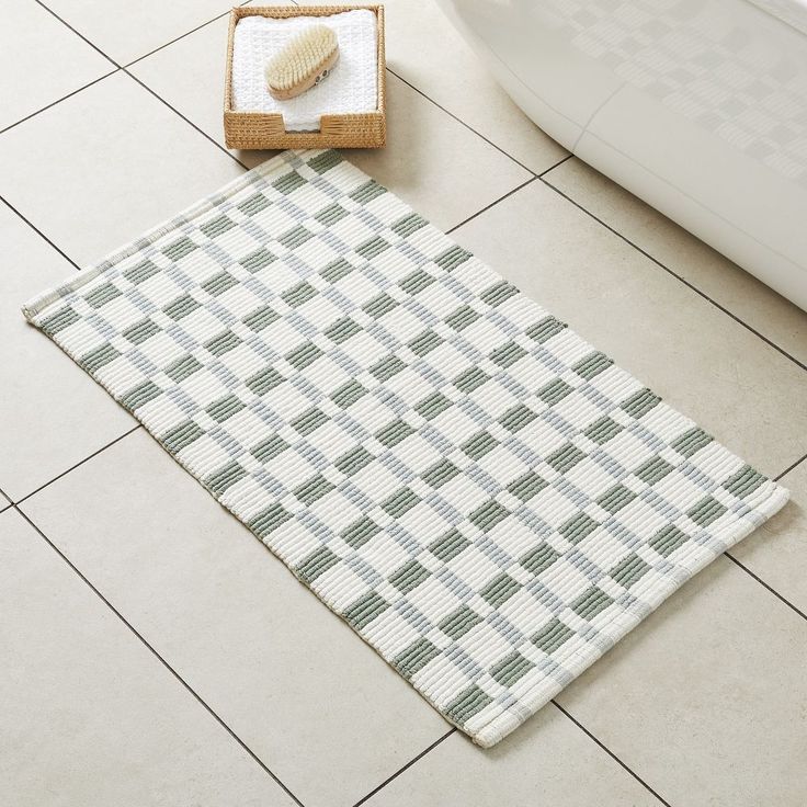 a bathroom with a white toilet and green checkered rug on the floor next to it