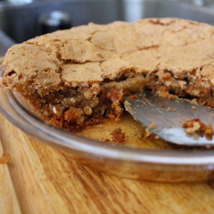 a close up of a pie on a wooden table with a slice missing from it