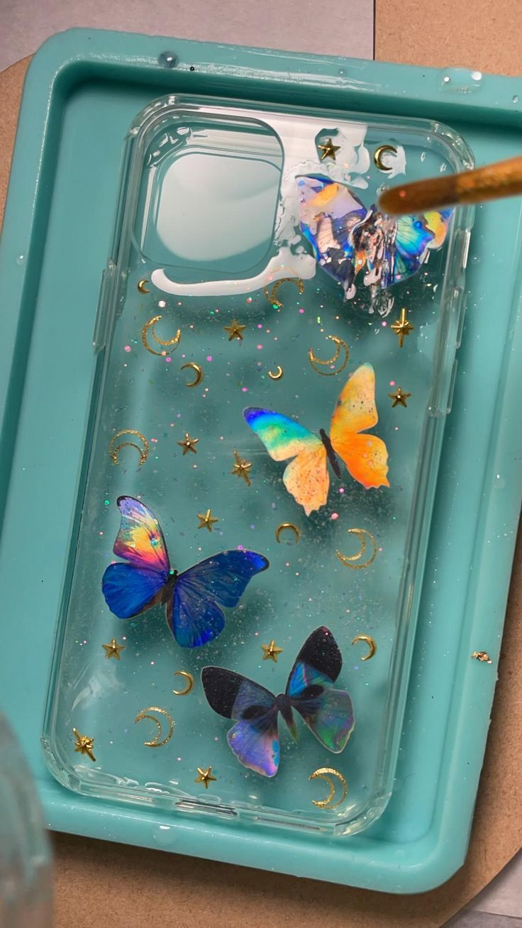 there are many colorful butterflies in the water on this phone case, and one is holding a brush