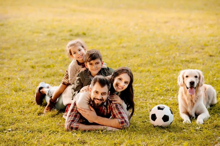 the family is posing for a photo with their dog and soccer ball in front of them