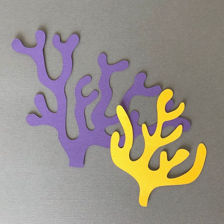 two pieces of cut out paper with yellow and purple sea corals on grey background