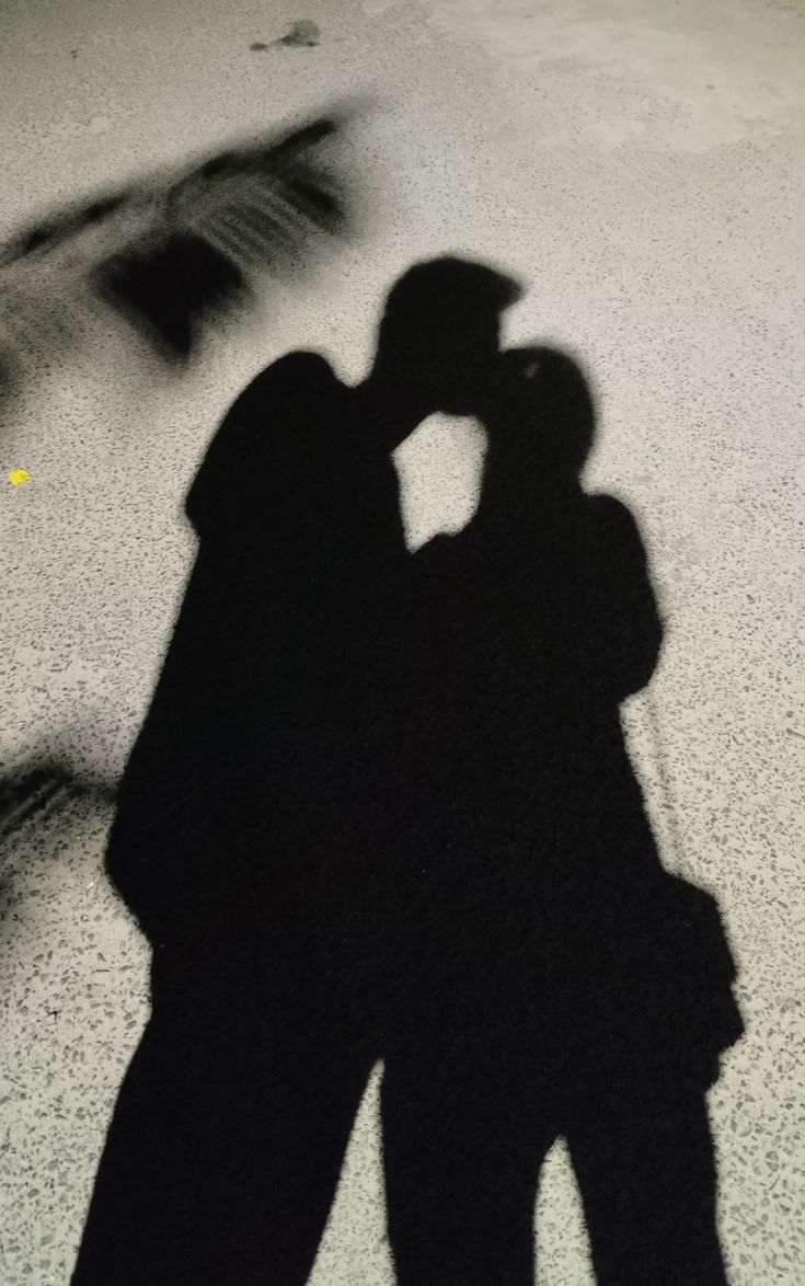 a shadow of two people kissing on the ground