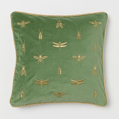 a green pillow with gold embroidered bees on it