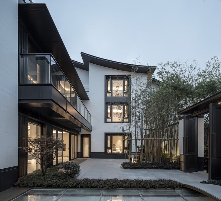 an exterior view of a modern house with trees in the yard and water feature on the ground